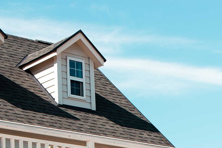 The close up image of authentic European house roof and roof window in blue sky with cloud. 