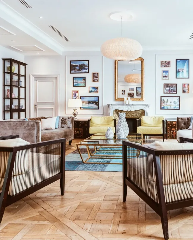 Elegant living room with striped chairs, pastel sofas, gold accents, and framed art on a white wall.
