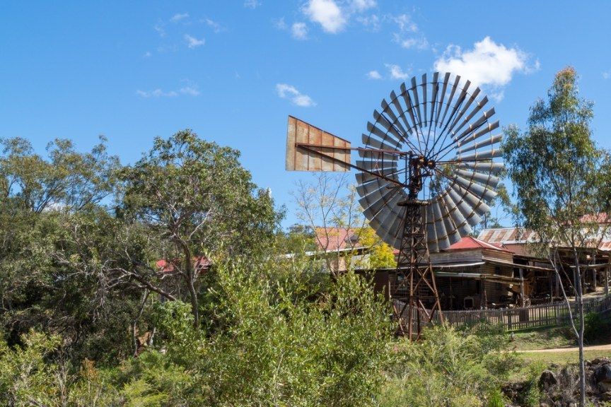 Rusty Windmill Overlooking Rustic Buildings — All Grind & Coat in Tablelands, QLD