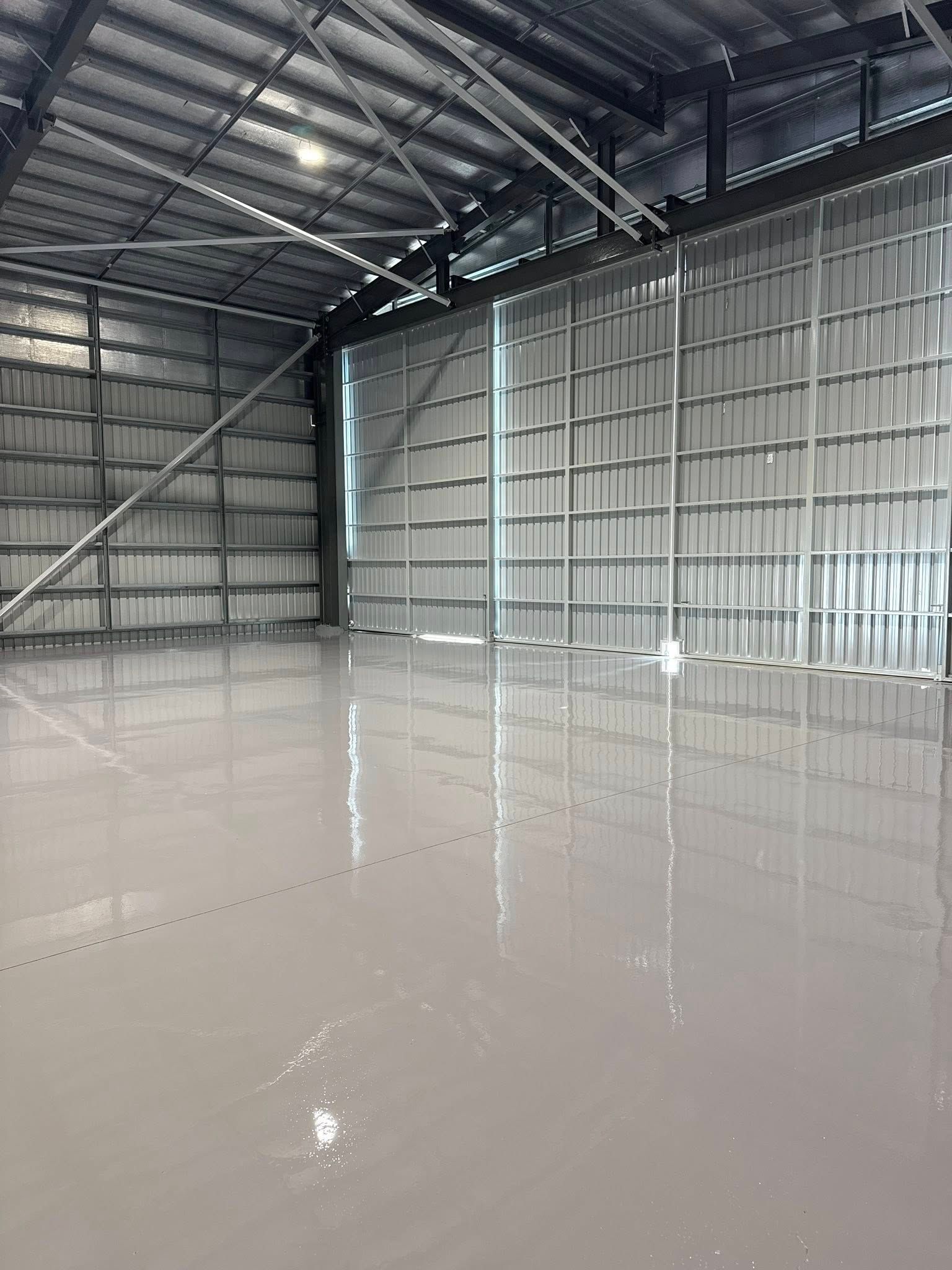 A kitchen with a gray epoxy floor and white cabinets — All Grind & Coat in Cairns, QLD
