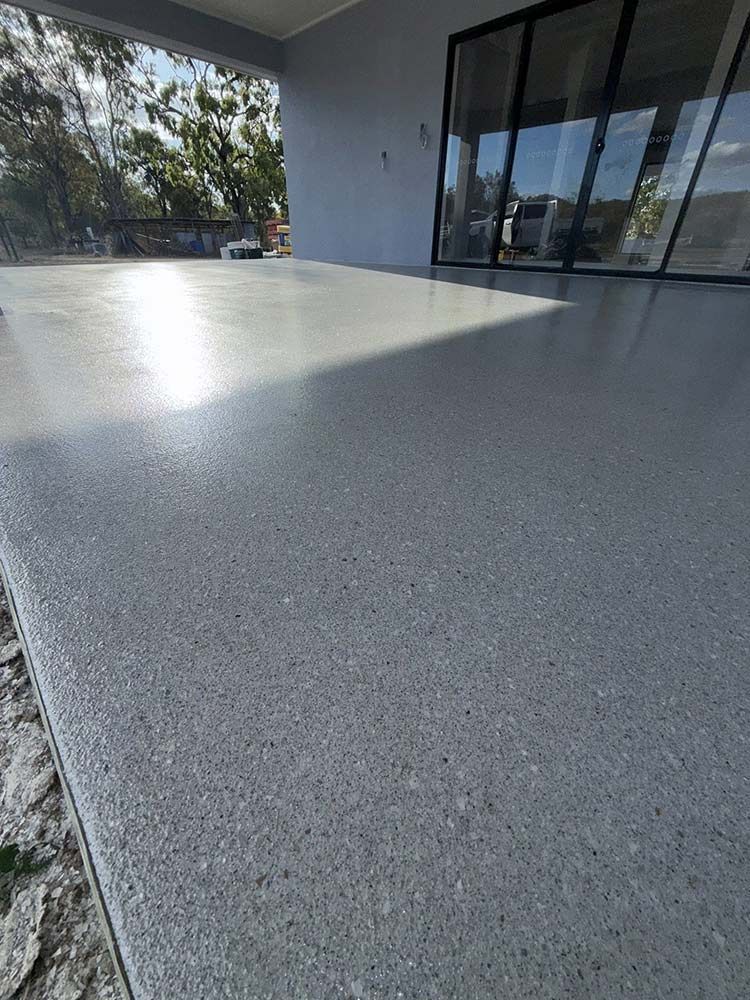 Polished gray concrete patio with a glossy finish, near sliding glass doors — All Grind & Coat in Cairns, QLD