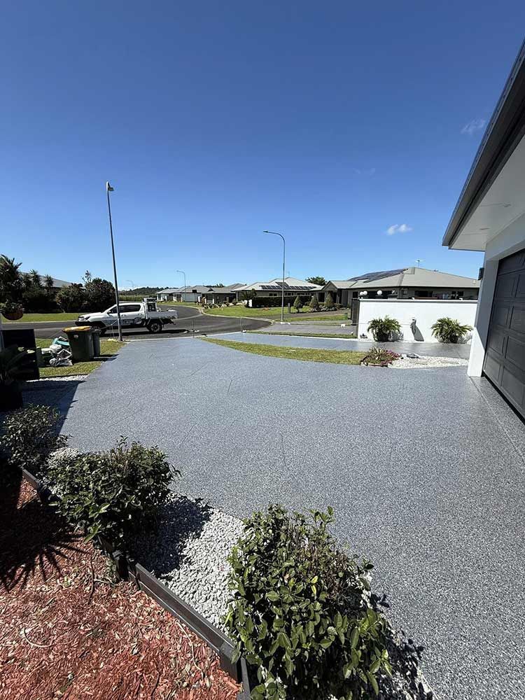 Driveway leading to houses under a blue sky. Bushes and landscaping on the sides — All Grind & Coat in Cairns, QLD