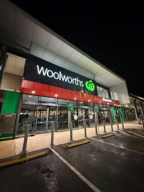 A Woolworths Store Is Lit Up At Night — All Grind & Coat in Cairns, QLD