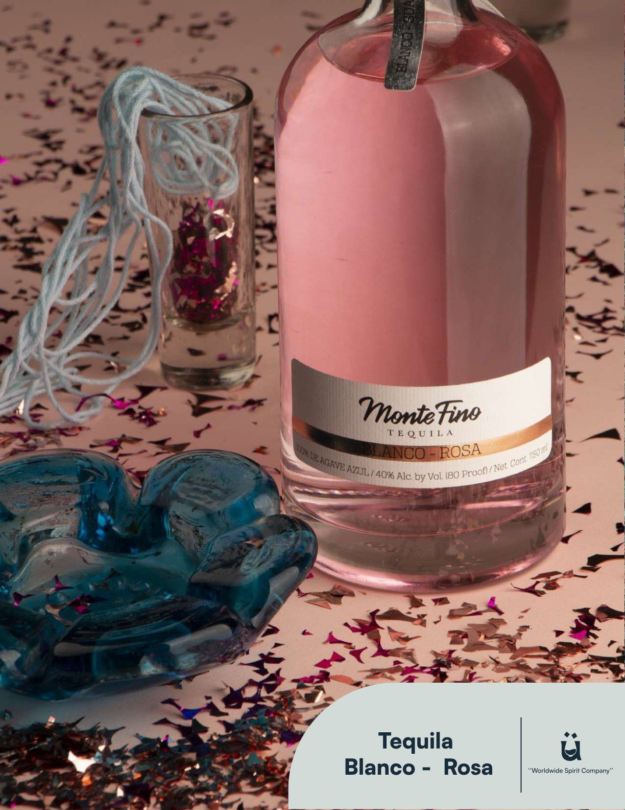 Bottle of pink tequila with a shot glass, confetti, and blue decorative item.