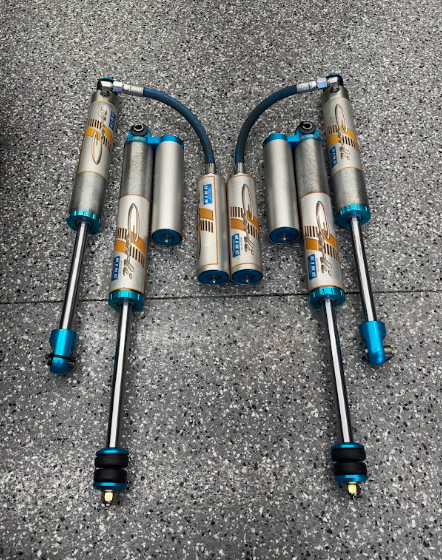 Set of silver and blue metal suspension shocks and dampers arranged on a gray surface