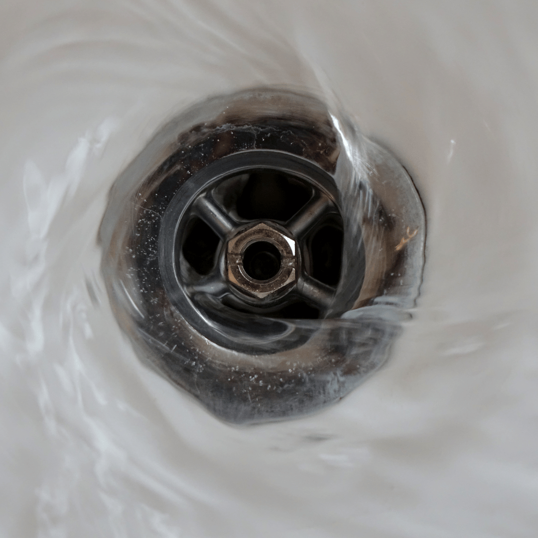 A close up of a sink drain with water coming out of it