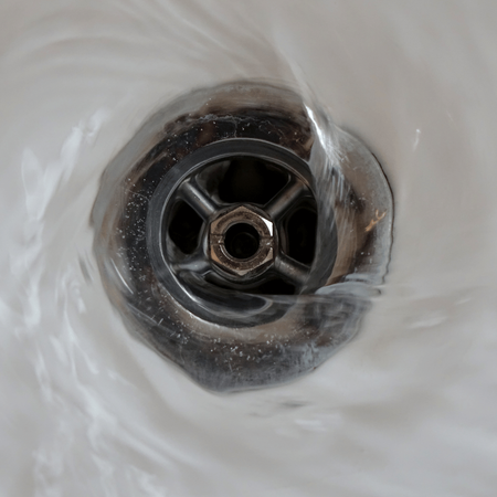 A close up of a sink drain with water coming out of it