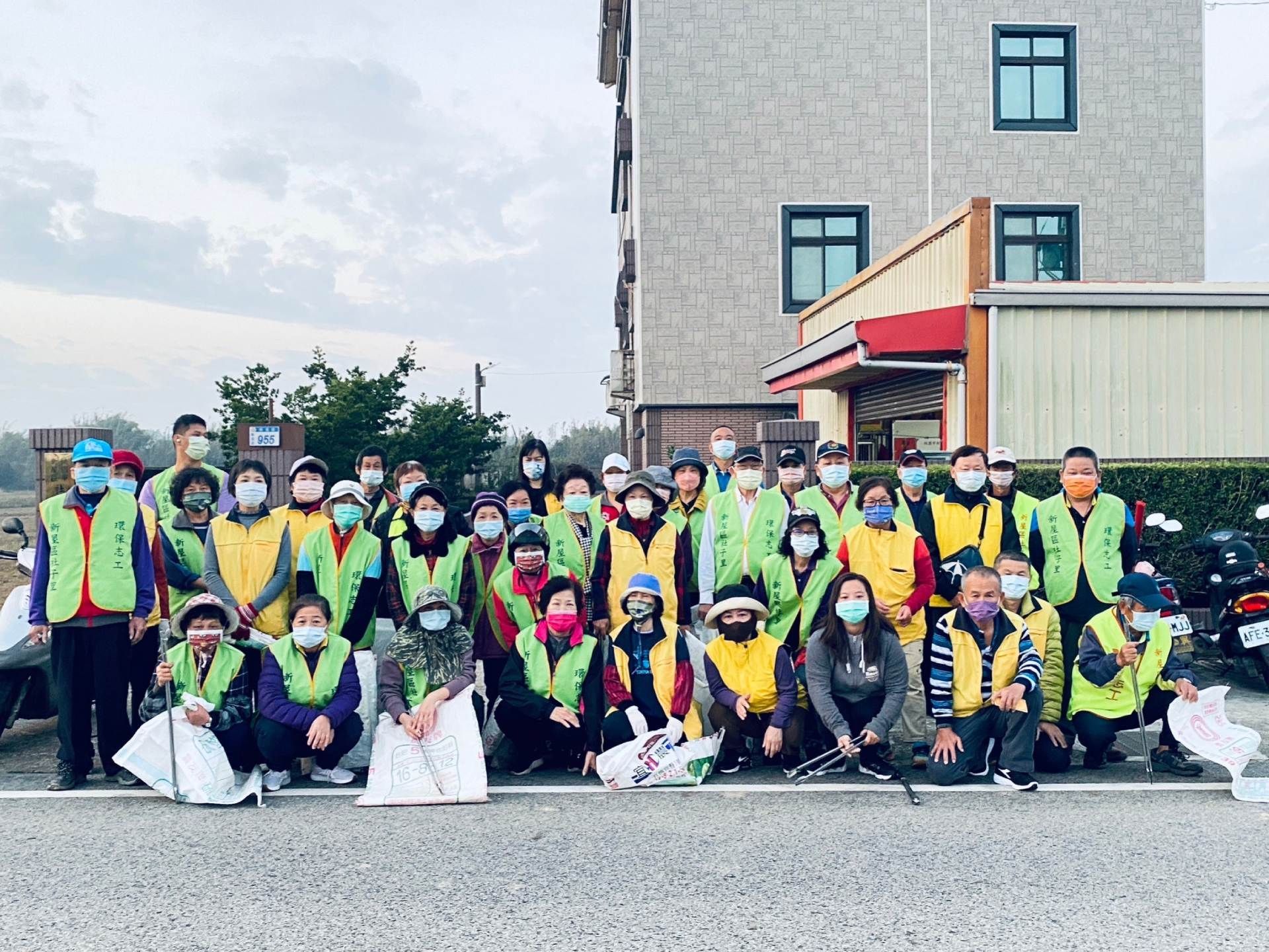 A group of people wearing masks are posing for a picture in front of a building.
