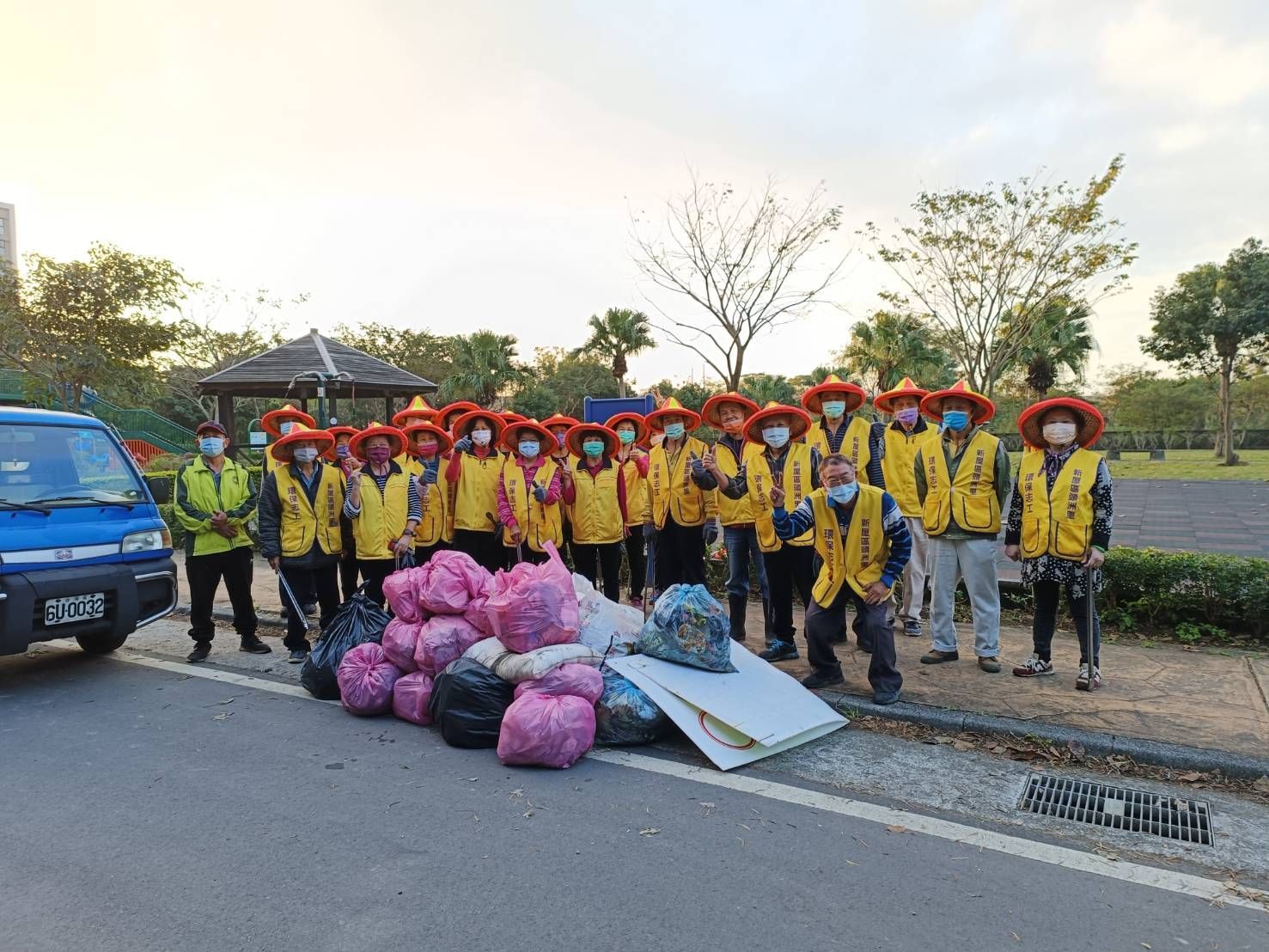 A group of people are standing in front of a pile of trash.