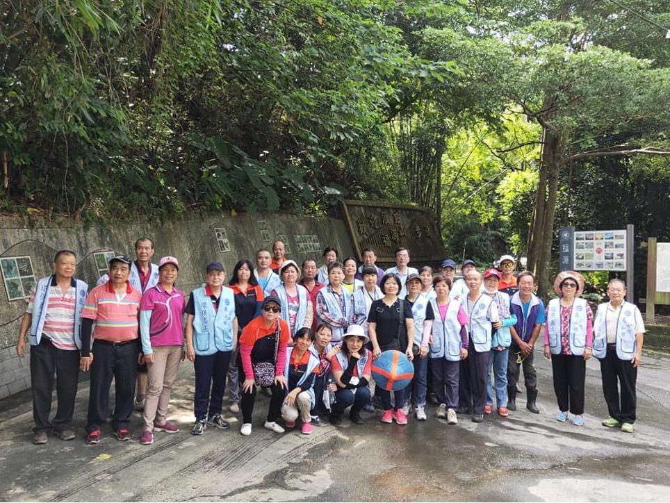 A large group of people are posing for a picture in a park.