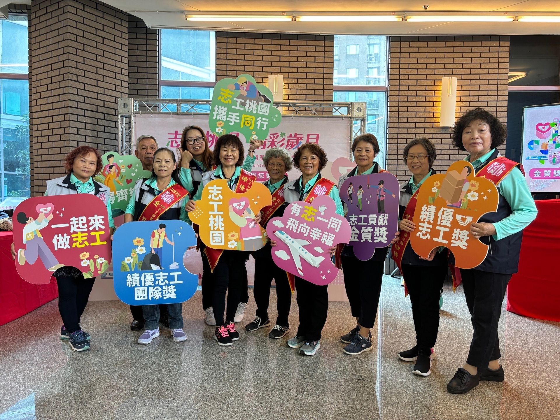 一群志工在活動中舉著標語，穿著統一的襯衫。