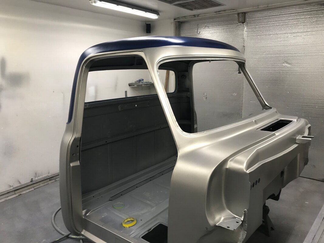 A truck is being painted in a paint booth.