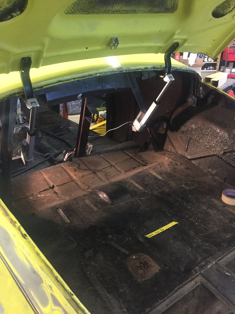 The trunk of a yellow car with the hood open
