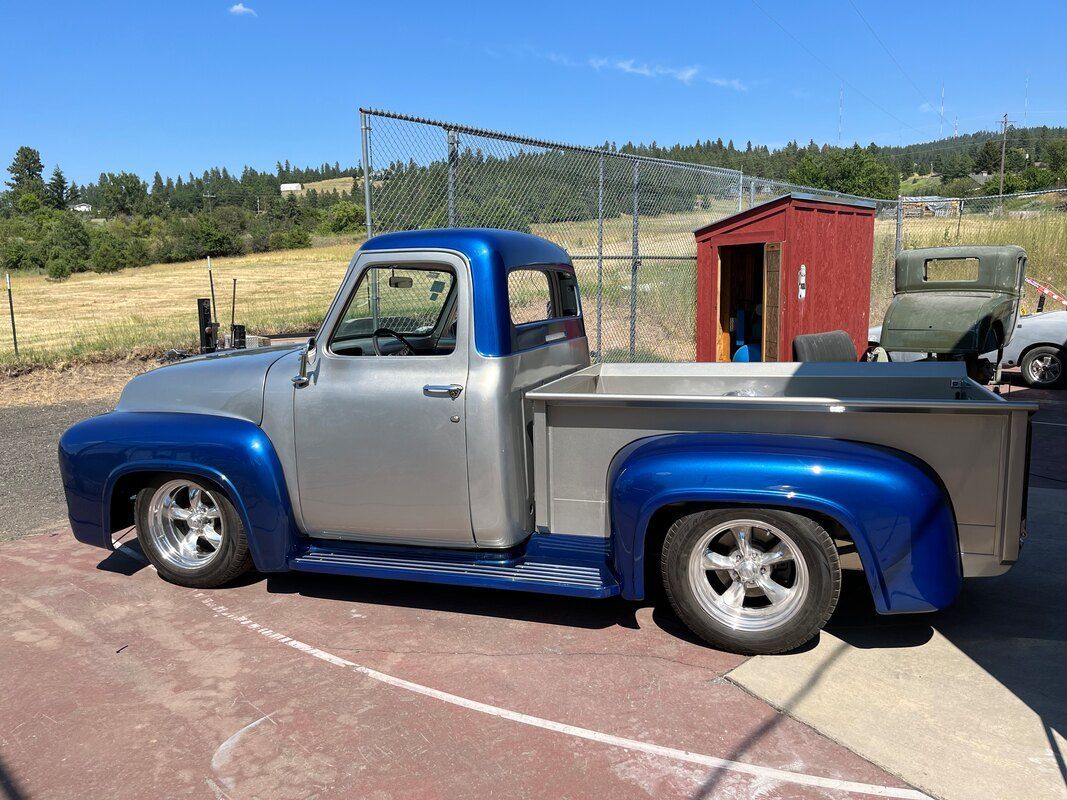 A silver and blue truck is parked in a parking lot.