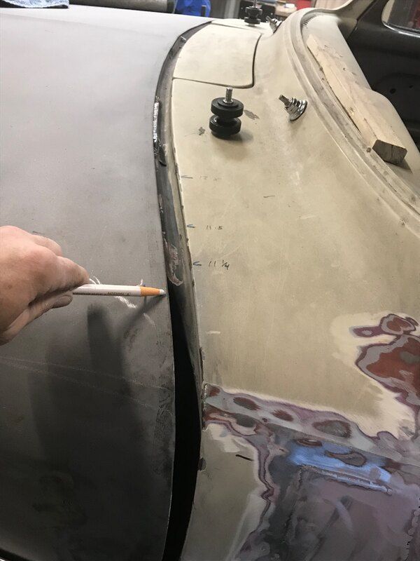 A person is holding a pencil and pointing at a corner of a car.