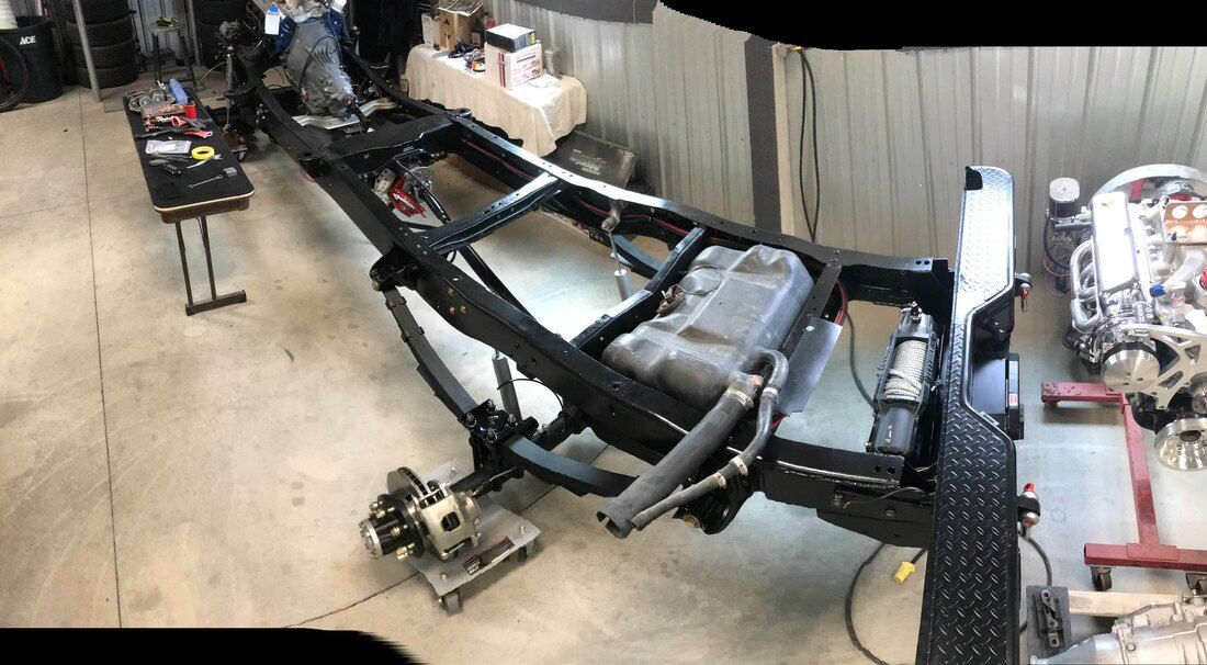 A car frame is sitting on the floor in a garage.