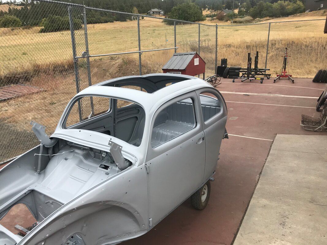 A white car with a sunroof is sitting in a parking lot.