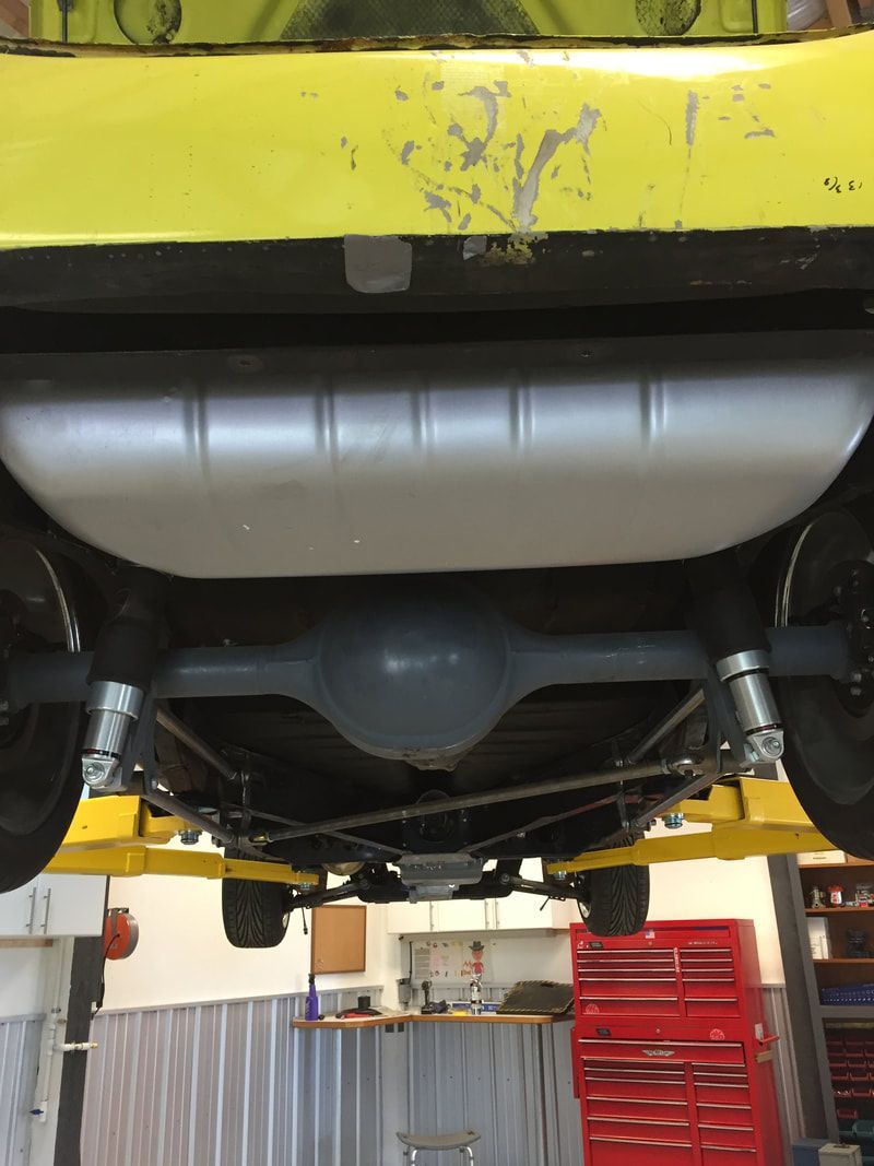A yellow car is on a lift in a garage
