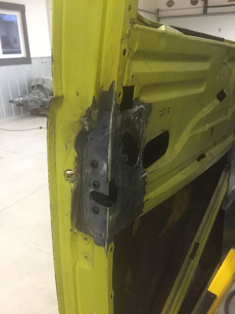A yellow car door is being repaired in a garage.