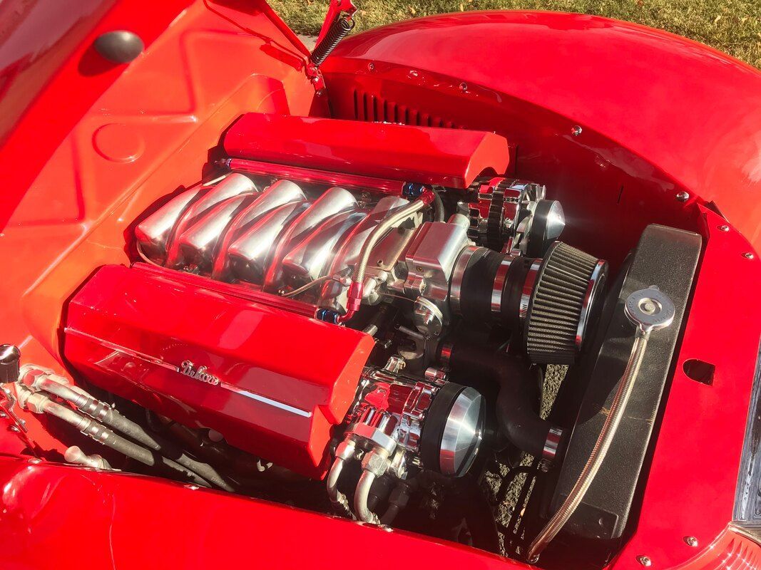 A close up of a red car engine with the hood open