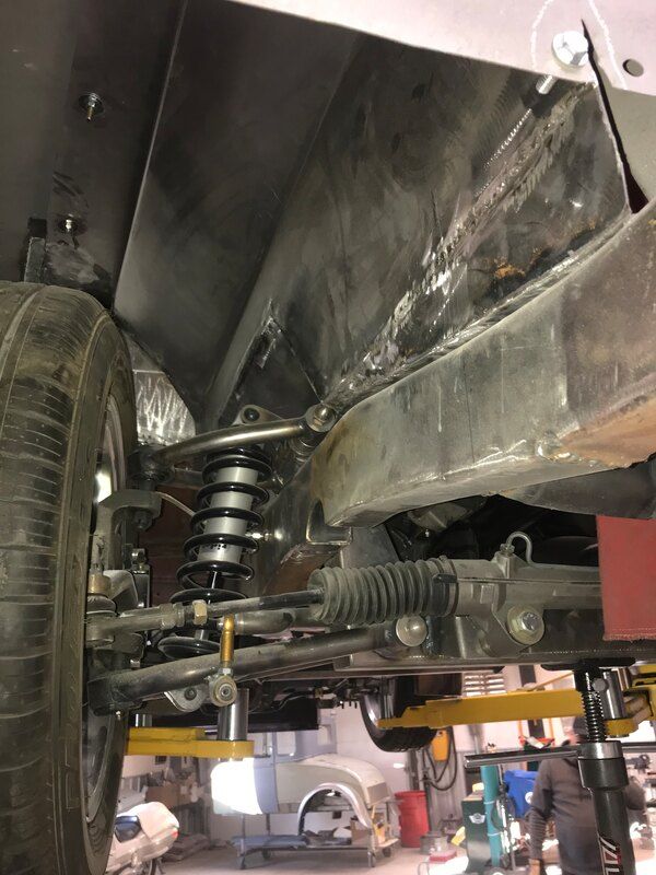 The underside of a car is being worked on in a garage.