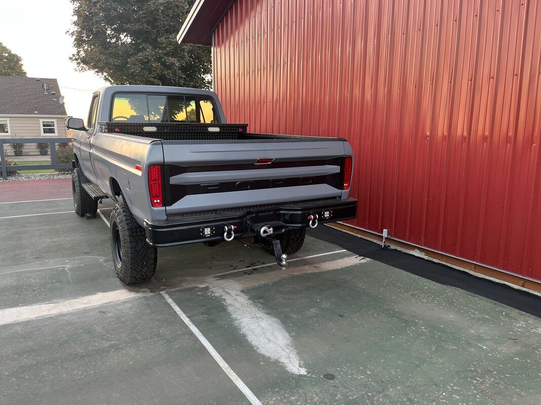 A truck is parked in front of a red barn.