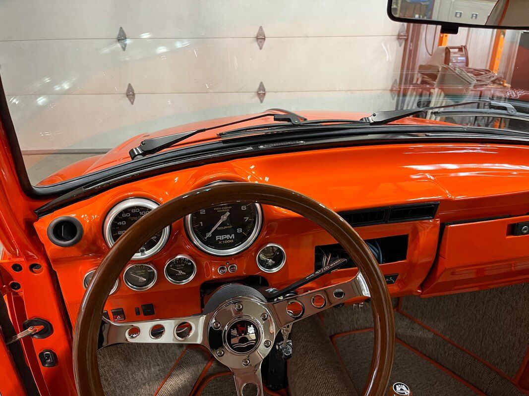 The interior of an orange car with a wooden steering wheel