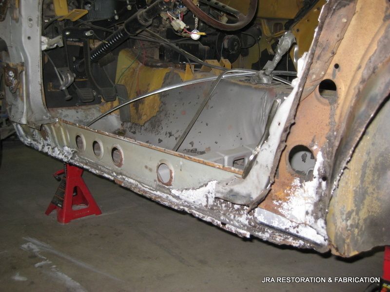 A rusty car is sitting on a red jack stand