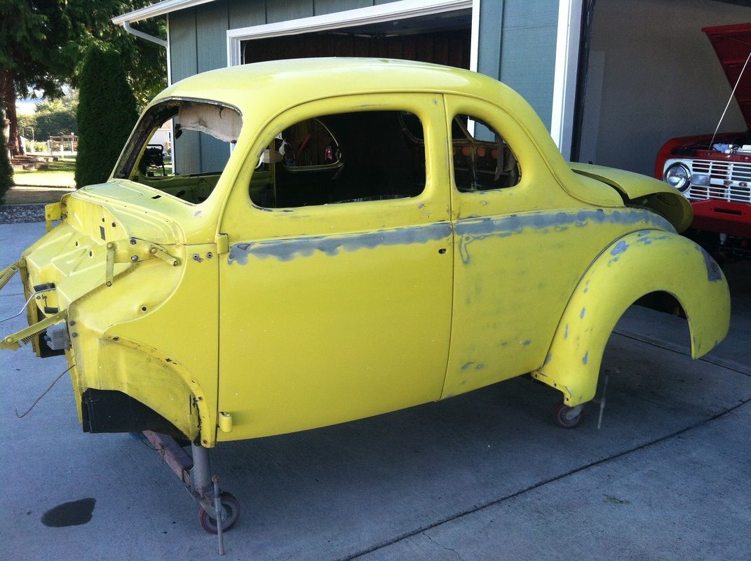 A yellow car is sitting in front of a garage