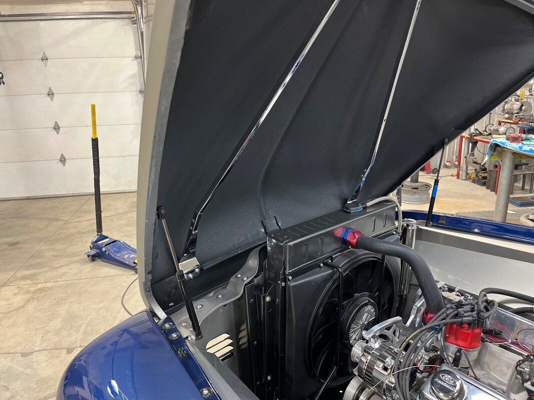 The hood of a blue car is open and the engine is visible.