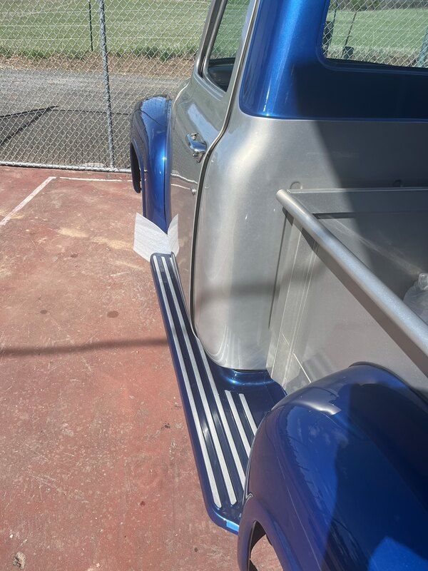 A blue and silver truck is parked in a parking lot