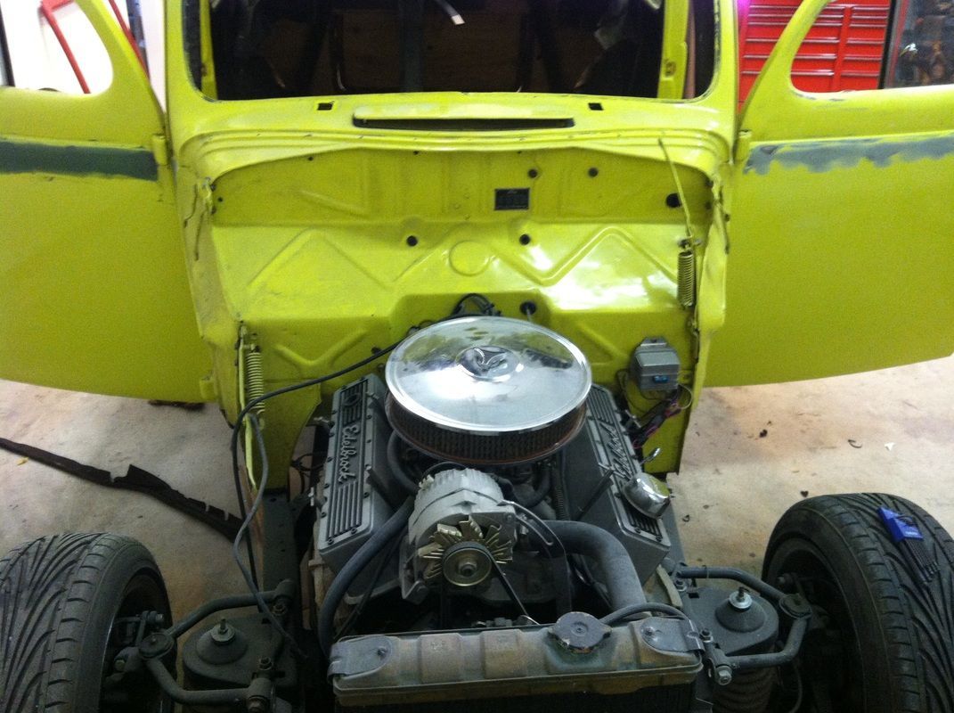 A yellow car with the hood open and the engine exposed