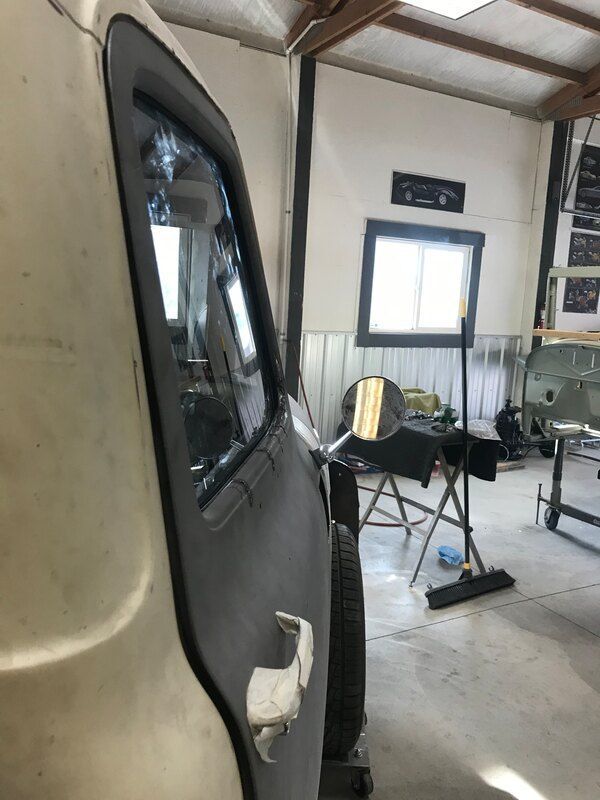 A white van is sitting in a garage next to a window.