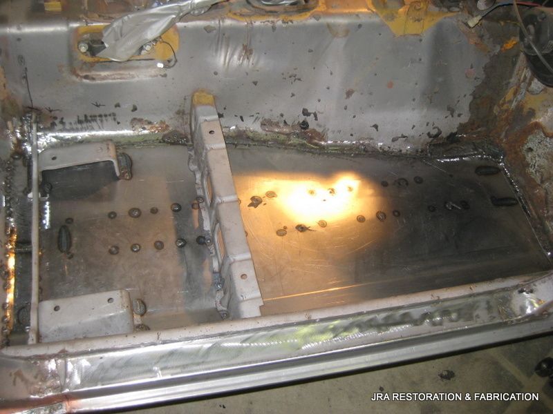 A car is being restored and a light is shining on the bottom of the car.