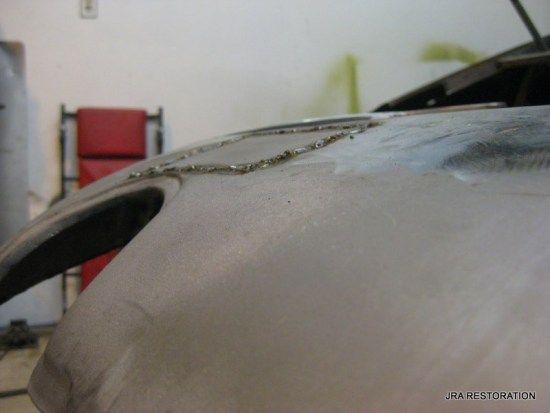 A close up of a car hood with a red chair in the background