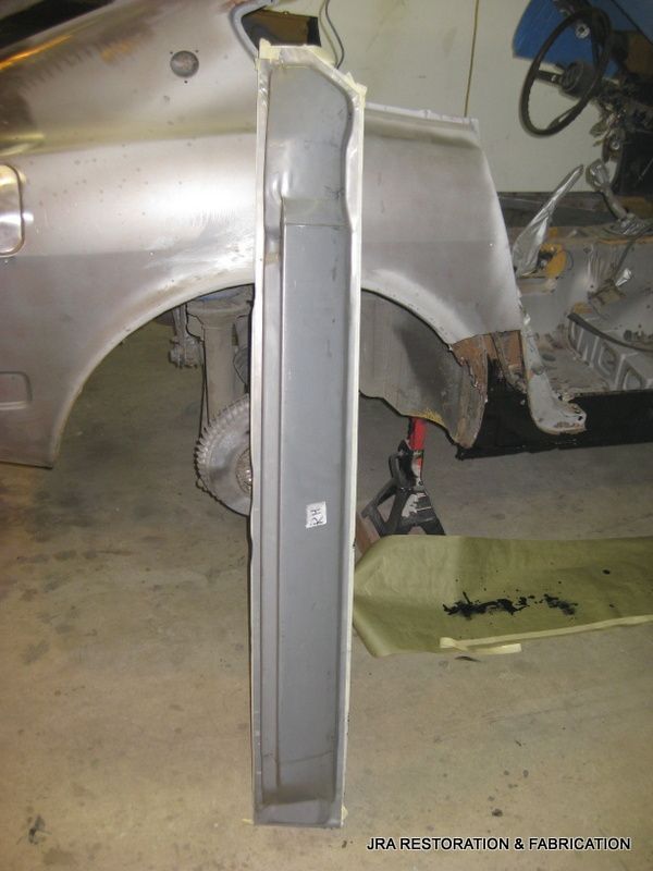 A piece of metal is sitting on the ground next to a car fender.