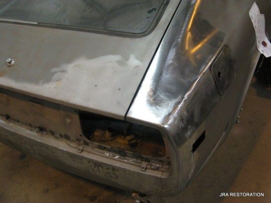 A silver car is being restored by a restoration company