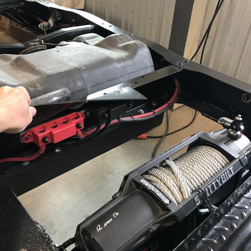 A person is working on a vehicle with a winch attached to it.