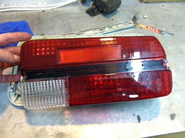 A person is holding a red car tail light on a table