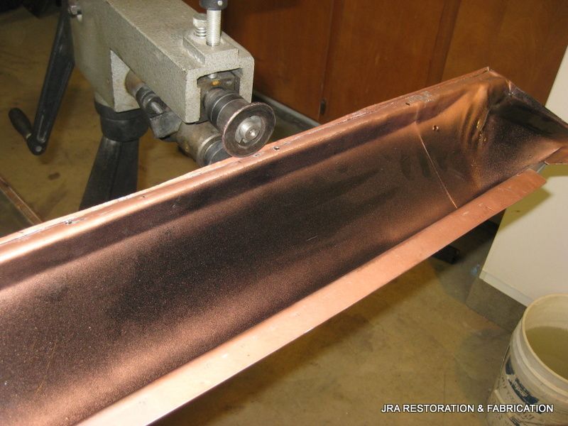A piece of copper is being rolled on a machine