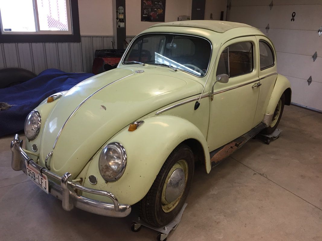 A yellow volkswagen beetle is parked in a garage.