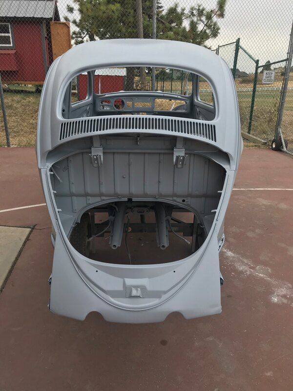 A white car with the trunk open is sitting on a basketball court.