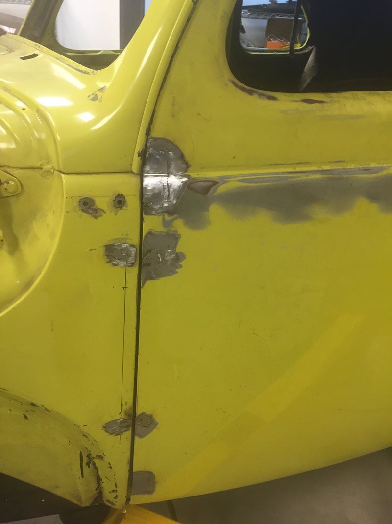 A yellow truck is sitting on a lift in a garage.