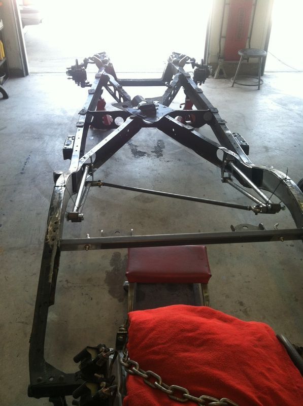 A car frame is sitting on the floor in a garage