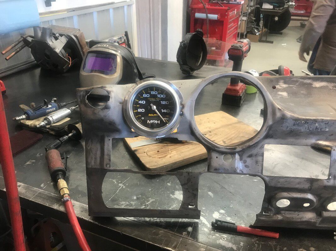 A welding helmet is sitting on a table next to a gauge.