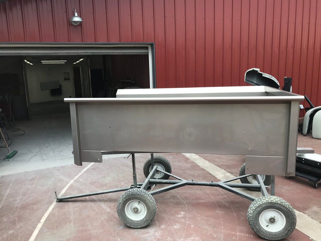 A stainless steel cart is parked in front of a red garage door.