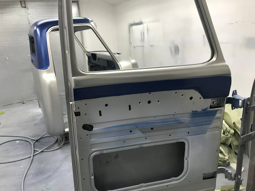 A truck door is being painted in a garage.