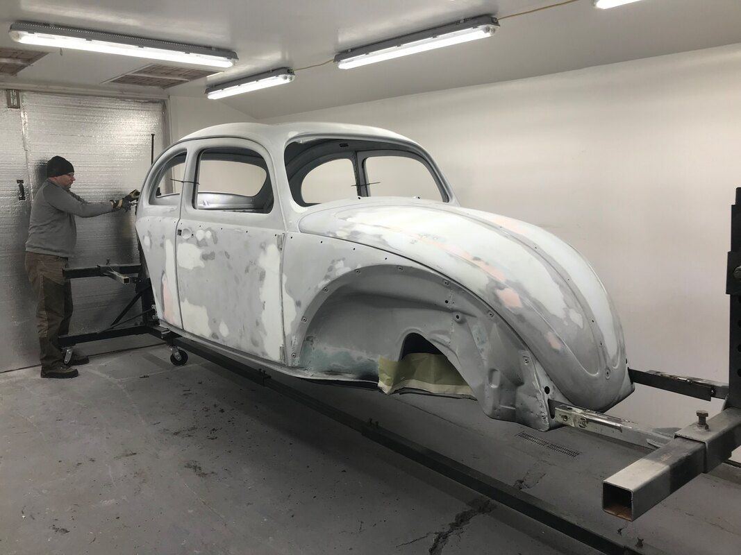 A man is working on a white car in a garage.