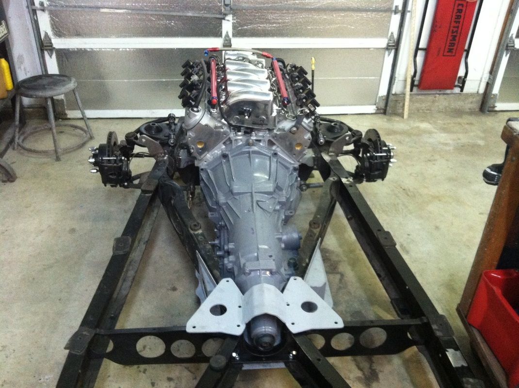 A car engine is sitting on a metal frame in a garage