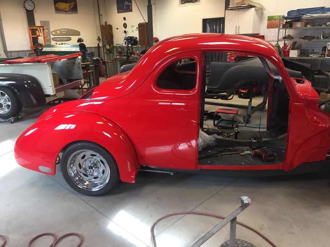 A red car is sitting in a garage with the door open